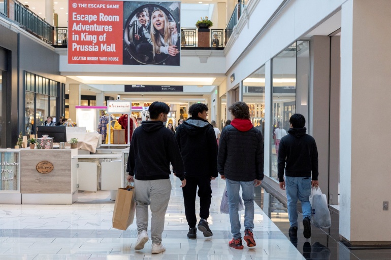 People carrying shopping bags walk inside a shopping mall